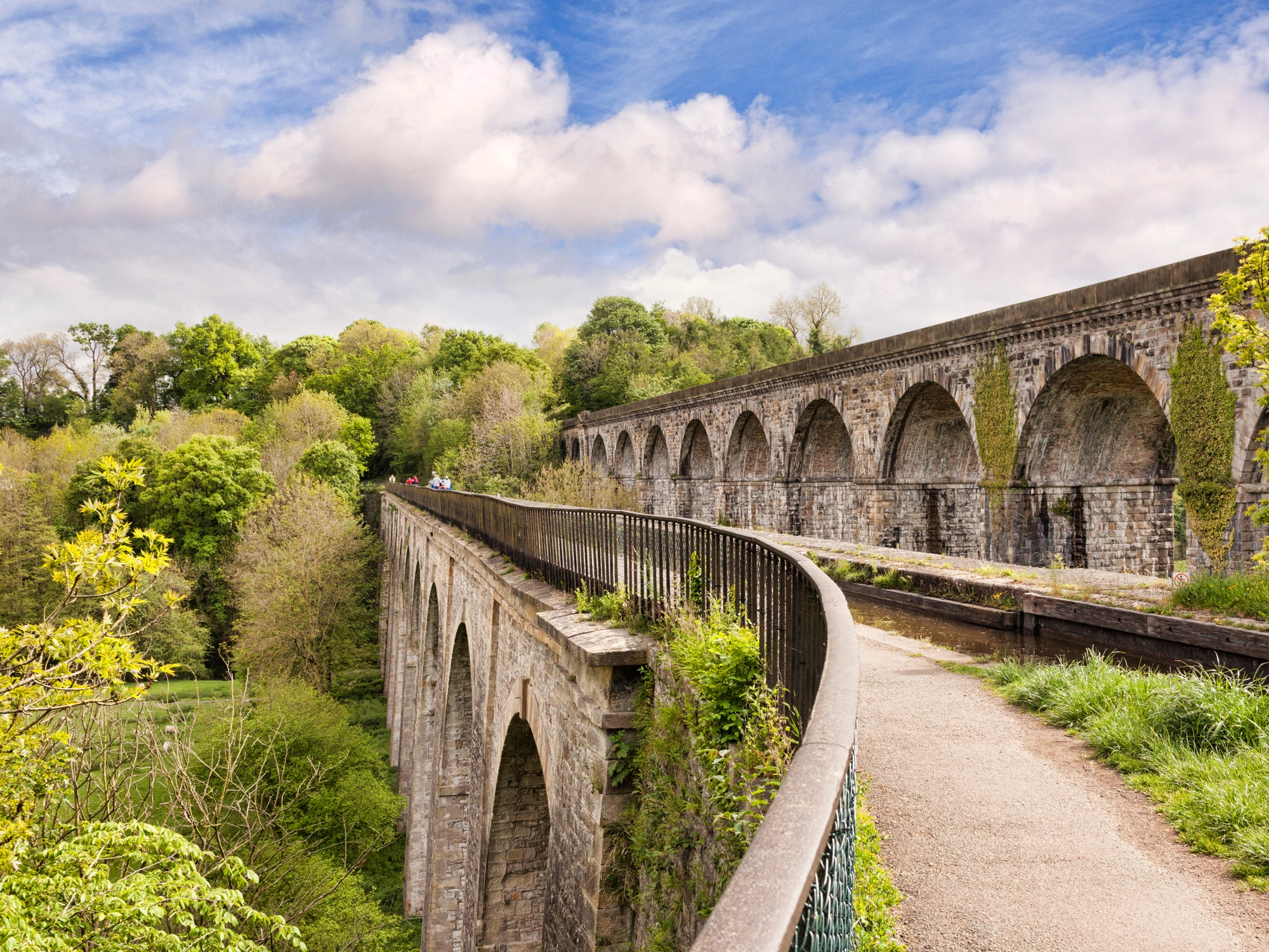 Stone-built viaduct in the UK surrounded by trees.