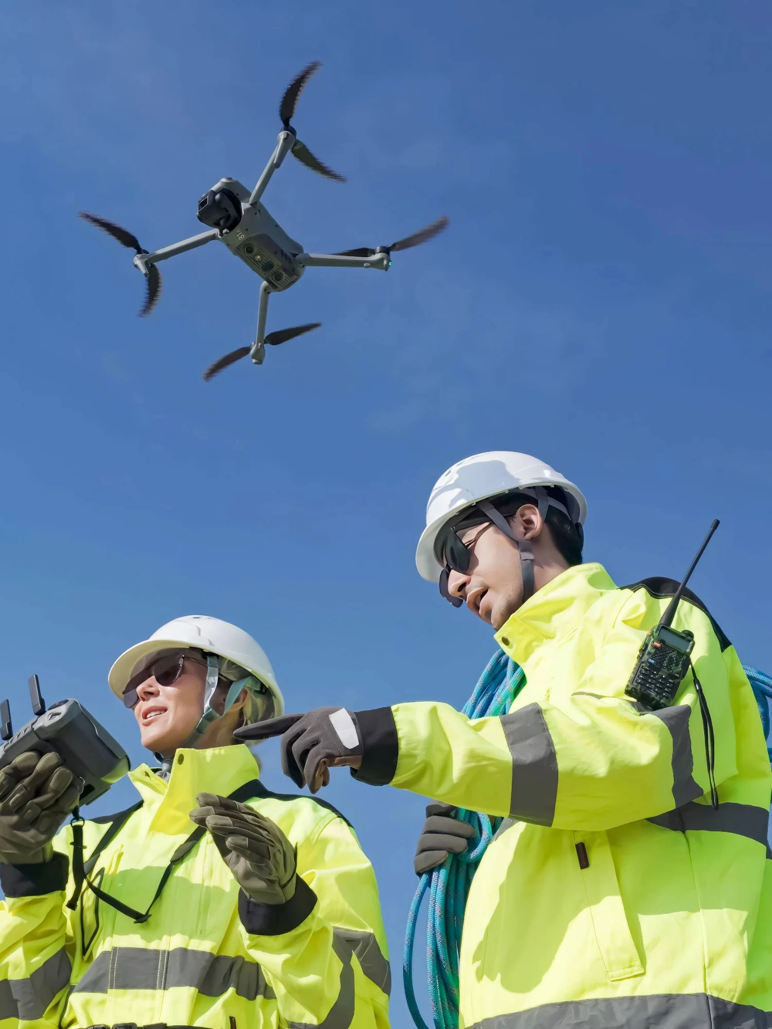 Two drone operators flying a drone in a clear blue sky.