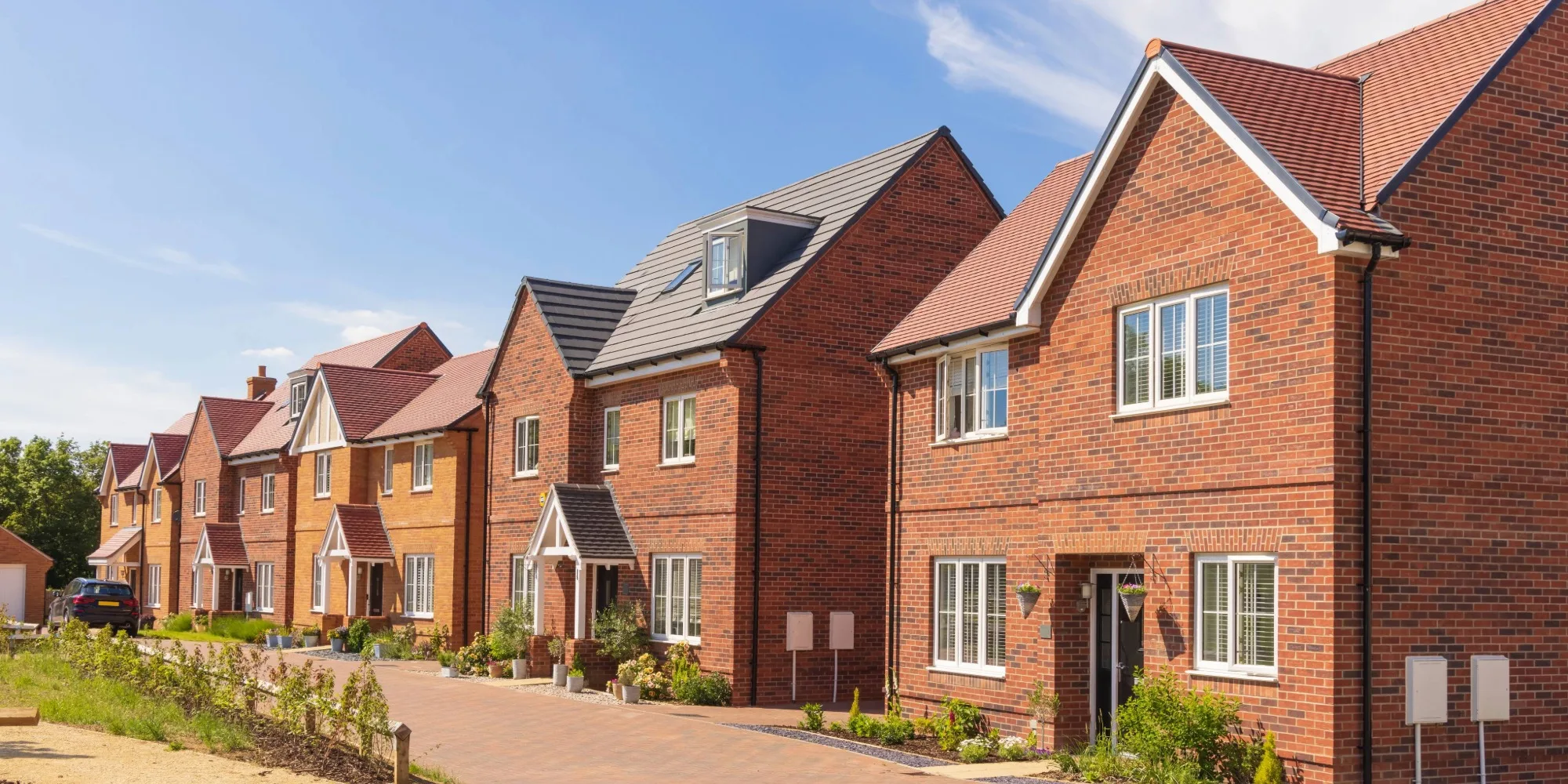 A row of British new build houses in a warm brick finish.