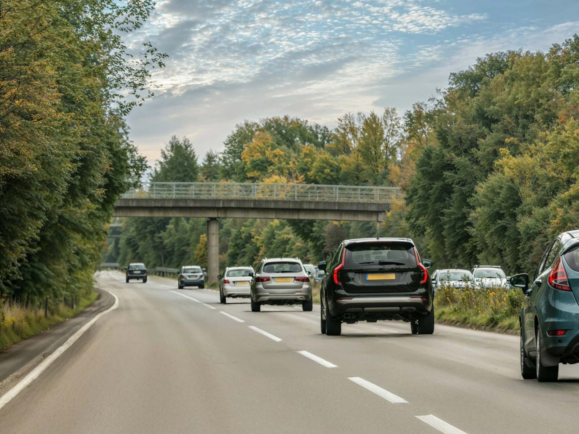 Cars driving along a UK highway and under a bridge on a cloudy day,