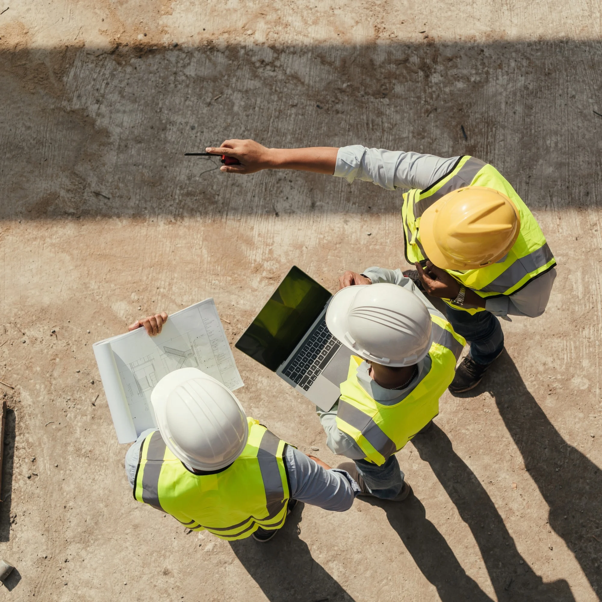 A team of surveyors wearing hi-vis vests and hard hats working on a construction site.