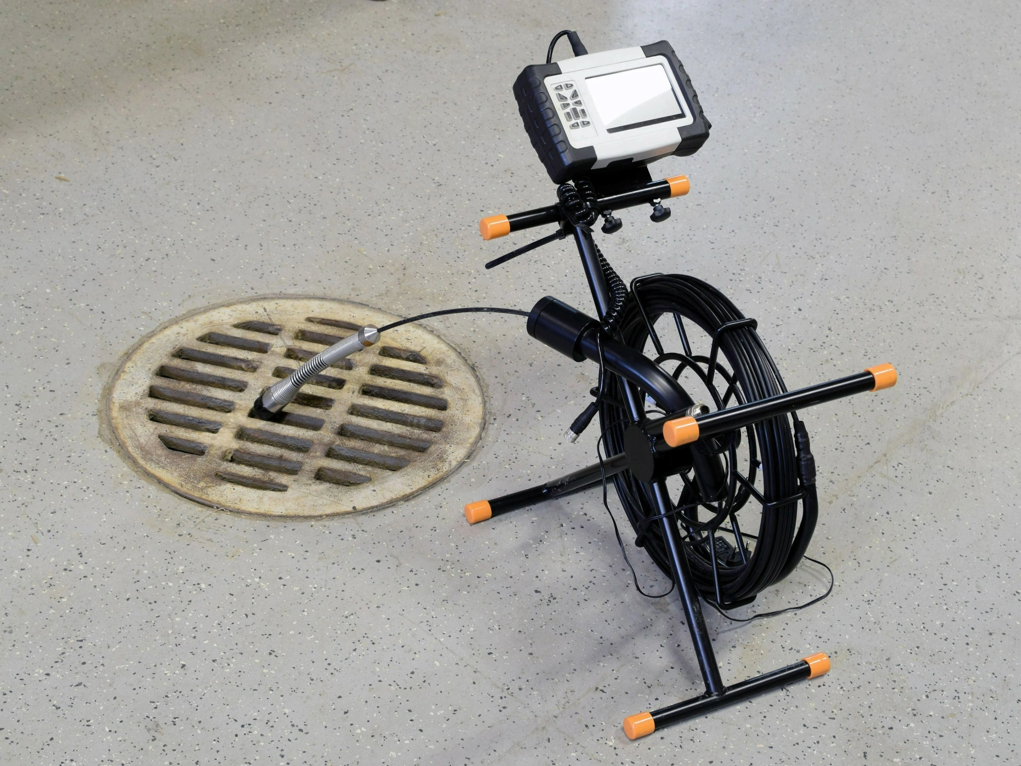 A remote reel camera with its reel down a drainhole.