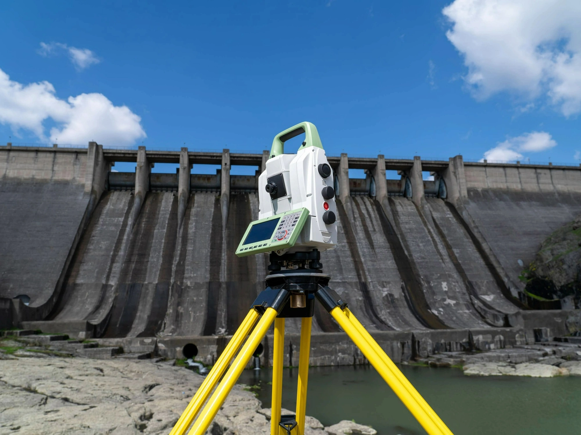 A total station position beside a reservoir in front of a tall man-made damn.