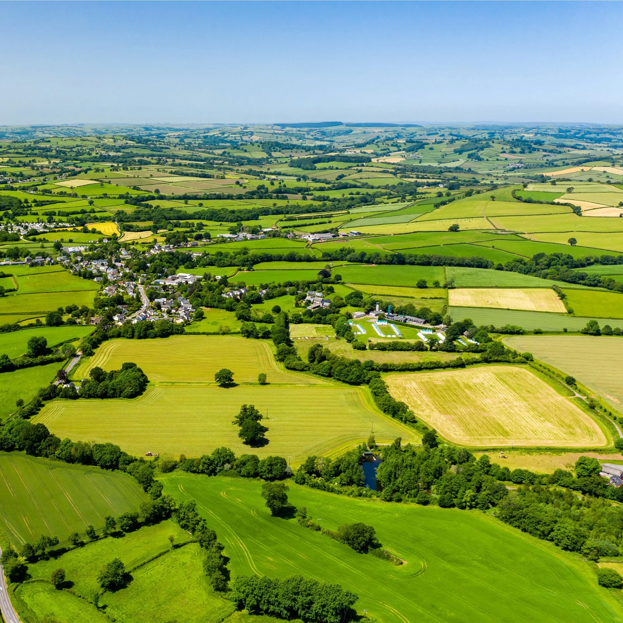 A drone shot of rural land with a small town in the centre.